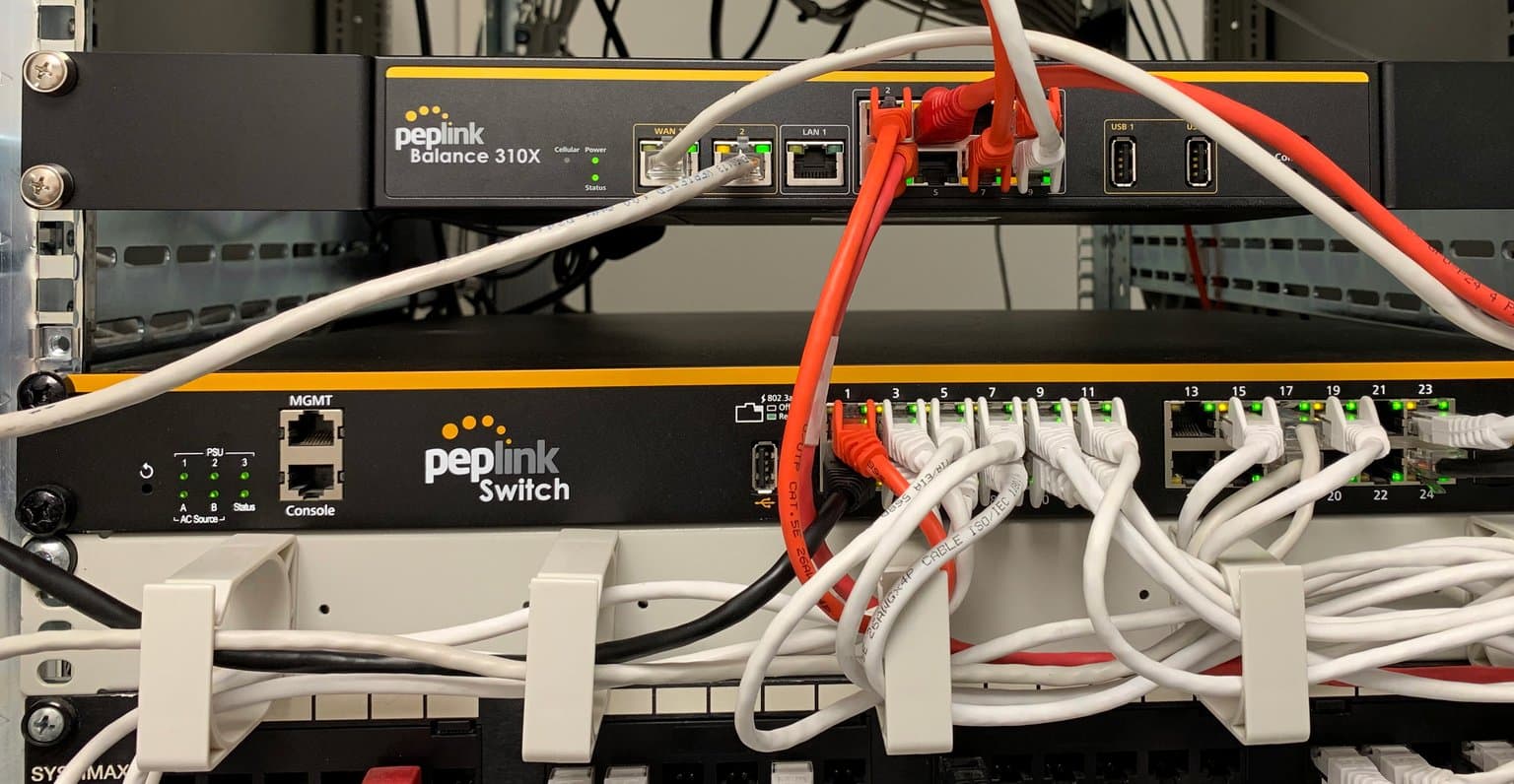 Peplink Balance 310X installed above a Peplink Switch in a server rack