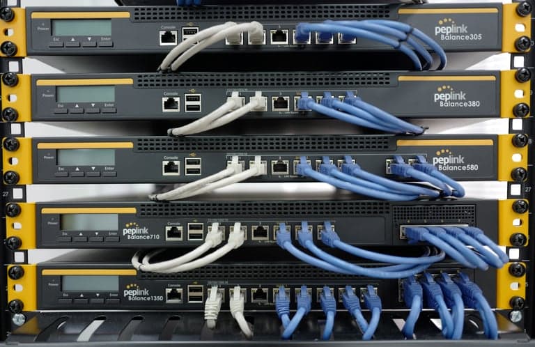 Rack of stacked Peplink Balance routers with patch cables