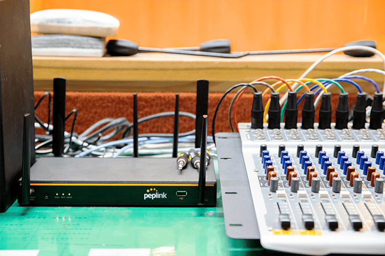 Peplink Balance 20X router beside an audio mixing console